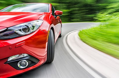 Red car drives around a corner